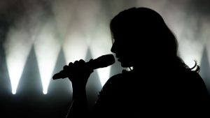Person som sjunger i trådlös mikrofon på en scen